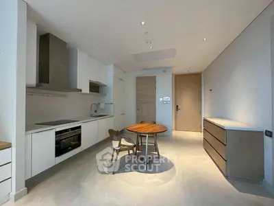 Modern kitchen with sleek cabinetry and dining area in minimalist apartment.