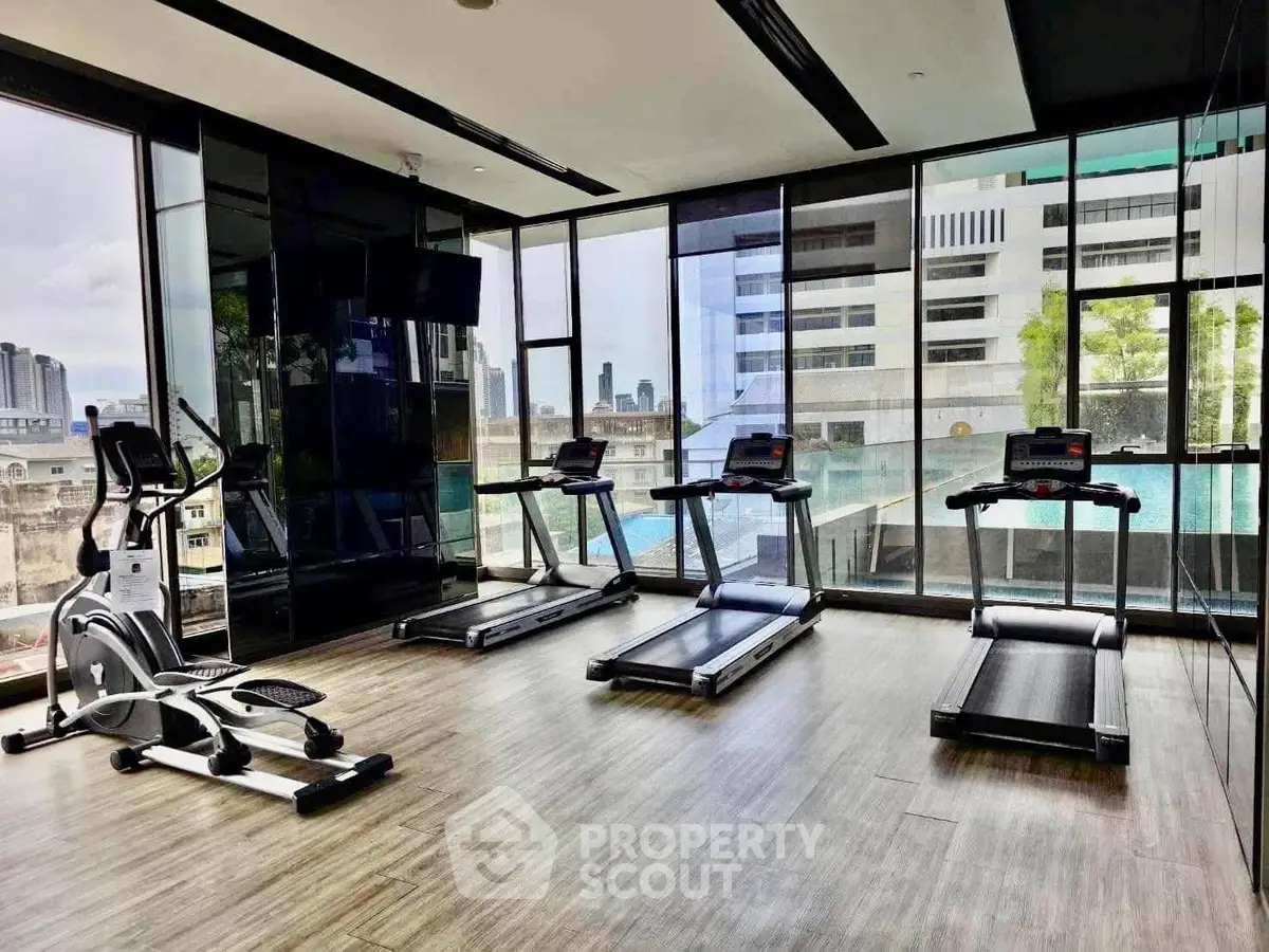 Modern gym with city view and state-of-the-art equipment in luxury building.