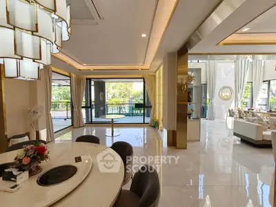 Luxurious open-plan living and dining area with modern decor and large windows offering garden views.