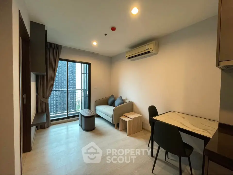 Modern living room with balcony view in high-rise apartment, featuring sleek furniture and air conditioning.