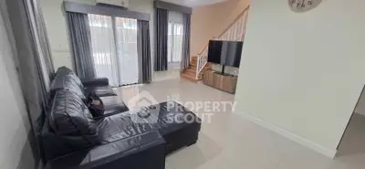 Spacious living room with sleek leather sofa and modern TV setup, perfect for relaxation and entertainment.