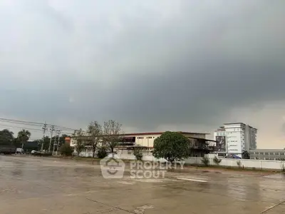 Expansive view of commercial building with ample parking space and overcast sky.