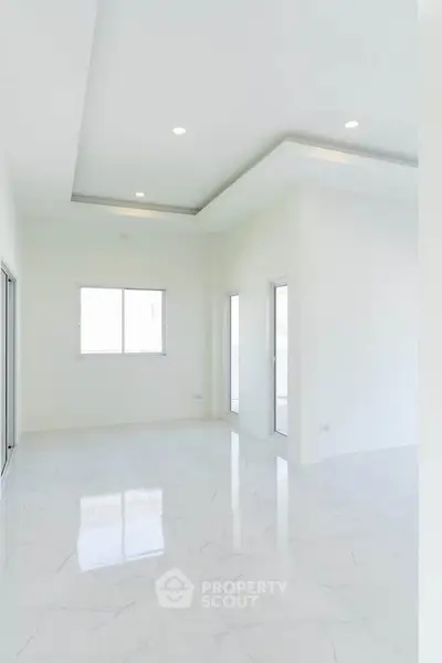 Spacious modern living room with white marble flooring and recessed lighting.