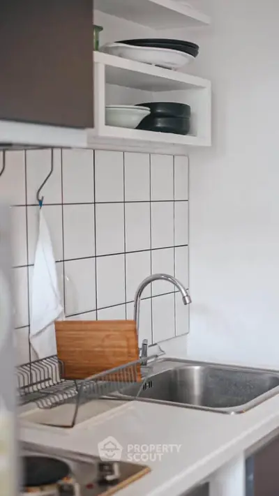 Modern kitchen with sleek sink and tiled backsplash, featuring open shelving and compact design.