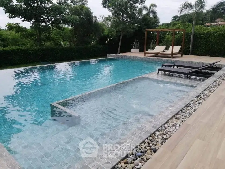 Luxurious outdoor swimming pool with sun loungers and lush greenery