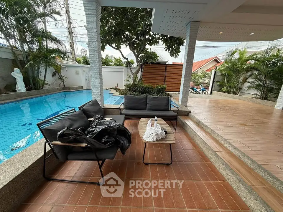 Luxurious poolside patio with modern seating and lush greenery, perfect for relaxation and entertainment.