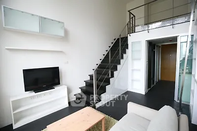 Modern loft-style living room with sleek staircase and minimalist decor