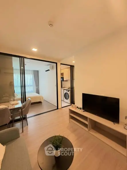 Modern apartment interior with open living room, dining area, and view into bedroom and kitchen.