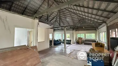 Spacious open-plan interior with exposed beams and large windows offering natural light.