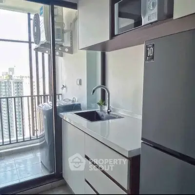 Modern kitchen with sleek appliances and balcony view in high-rise apartment.