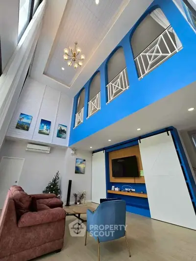 Stunning modern living room with high ceilings, elegant chandelier, and vibrant blue accents.