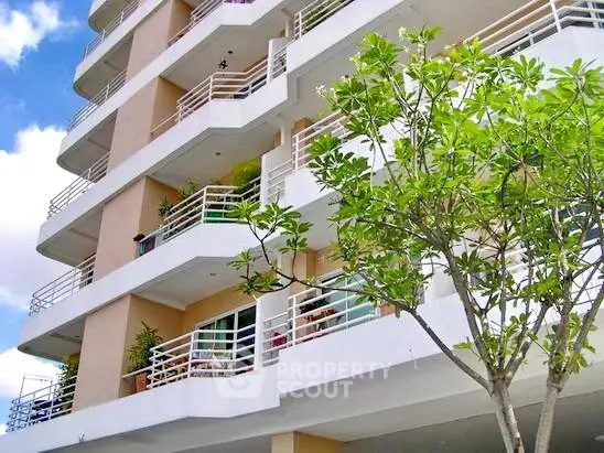 Modern multi-story building with spacious balconies and lush greenery