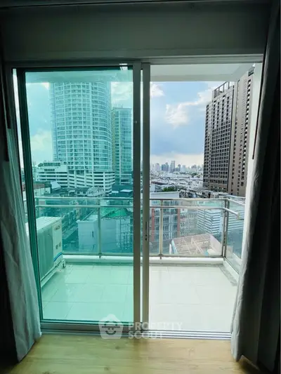 Stunning city view from modern apartment balcony with glass railing and sliding doors.