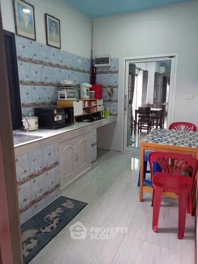 Charming kitchen with tiled walls and dining area, featuring modern appliances and colorful chairs.