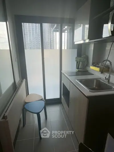 Compact kitchen with modern appliances and city view from window
