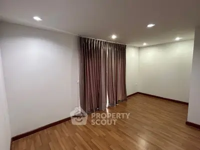 Spacious and well-lit living room with polished hardwood floors and elegant drapery, perfect for comfortable urban living.