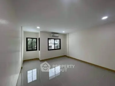 Spacious empty room with glossy tiled floor and large windows for natural light.