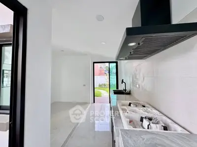 Modern kitchen with sleek design and open layout leading to a garden view.