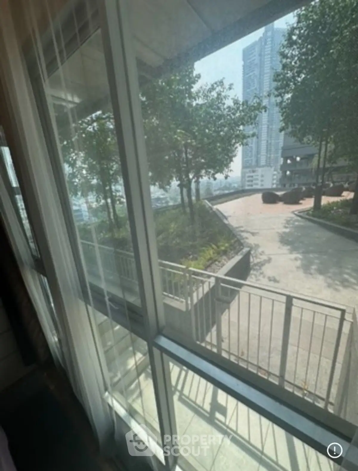 Spacious apartment with large windows offering a serene garden view, perfect for relaxation and natural light.