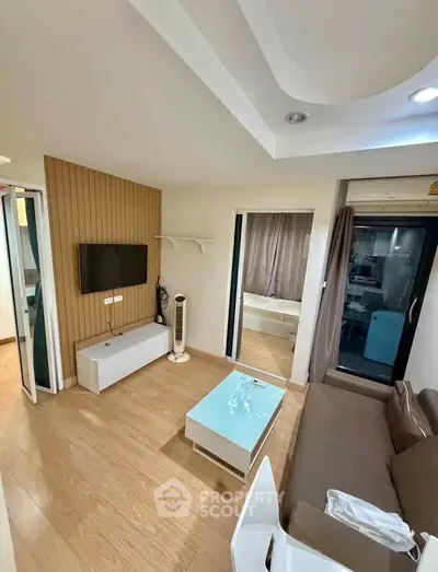 Modern living room with wooden flooring, wall-mounted TV, and cozy sofa in a stylish apartment.