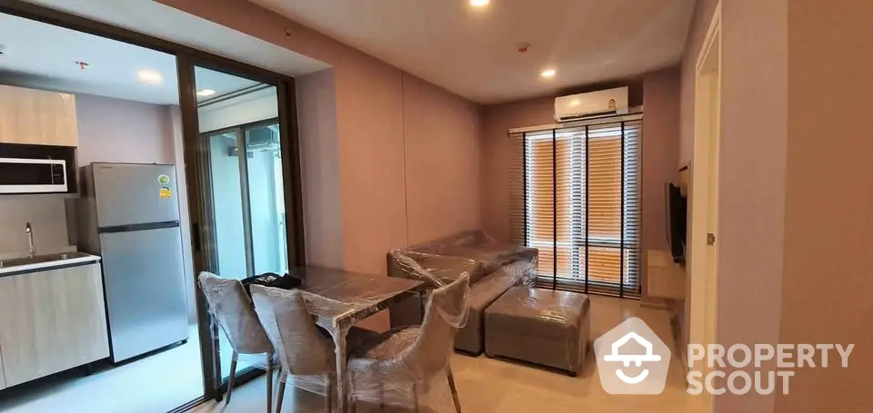 Modern living room with kitchen, featuring sleek furniture and large windows for natural light.