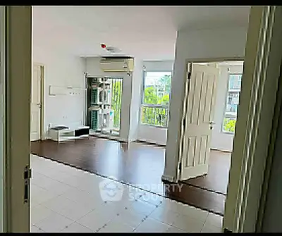 Spacious living room with wooden flooring and large windows offering natural light and garden view.