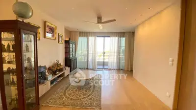 Spacious living room with elegant decor and large window offering natural light and balcony access.