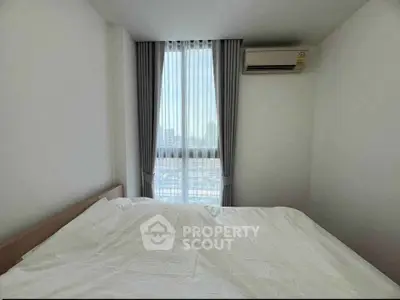 Bright bedroom with large window and air conditioning in modern apartment.