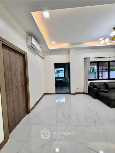 Spacious modern living room with elegant ceiling lights and large windows.
