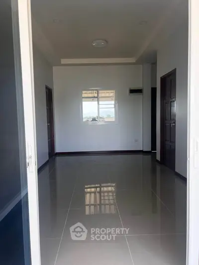 Spacious empty room with glossy tiled floor and large window view.
