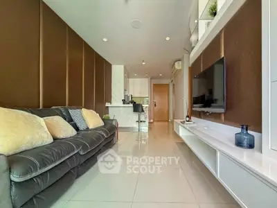 Modern living room with sleek design, featuring a plush sofa, wall-mounted TV, and open kitchen layout.
