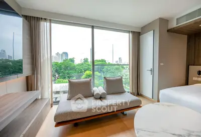 Modern living room with large windows offering a stunning city view, featuring a stylish sofa and elegant decor.