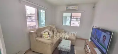 Cozy living room with modern sofa and large windows offering natural light.