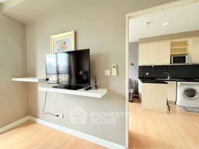 Modern apartment interior with TV, kitchen, and washing machine, featuring sleek design and open layout.
