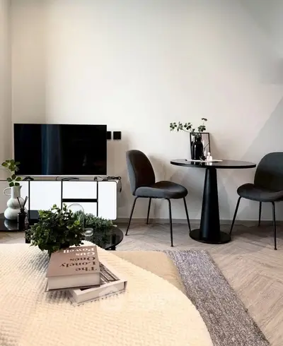 Modern living room with stylish furniture and decor, featuring a sleek TV setup and cozy dining area.