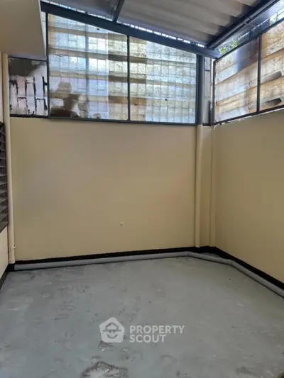Spacious enclosed balcony with high windows and concrete flooring