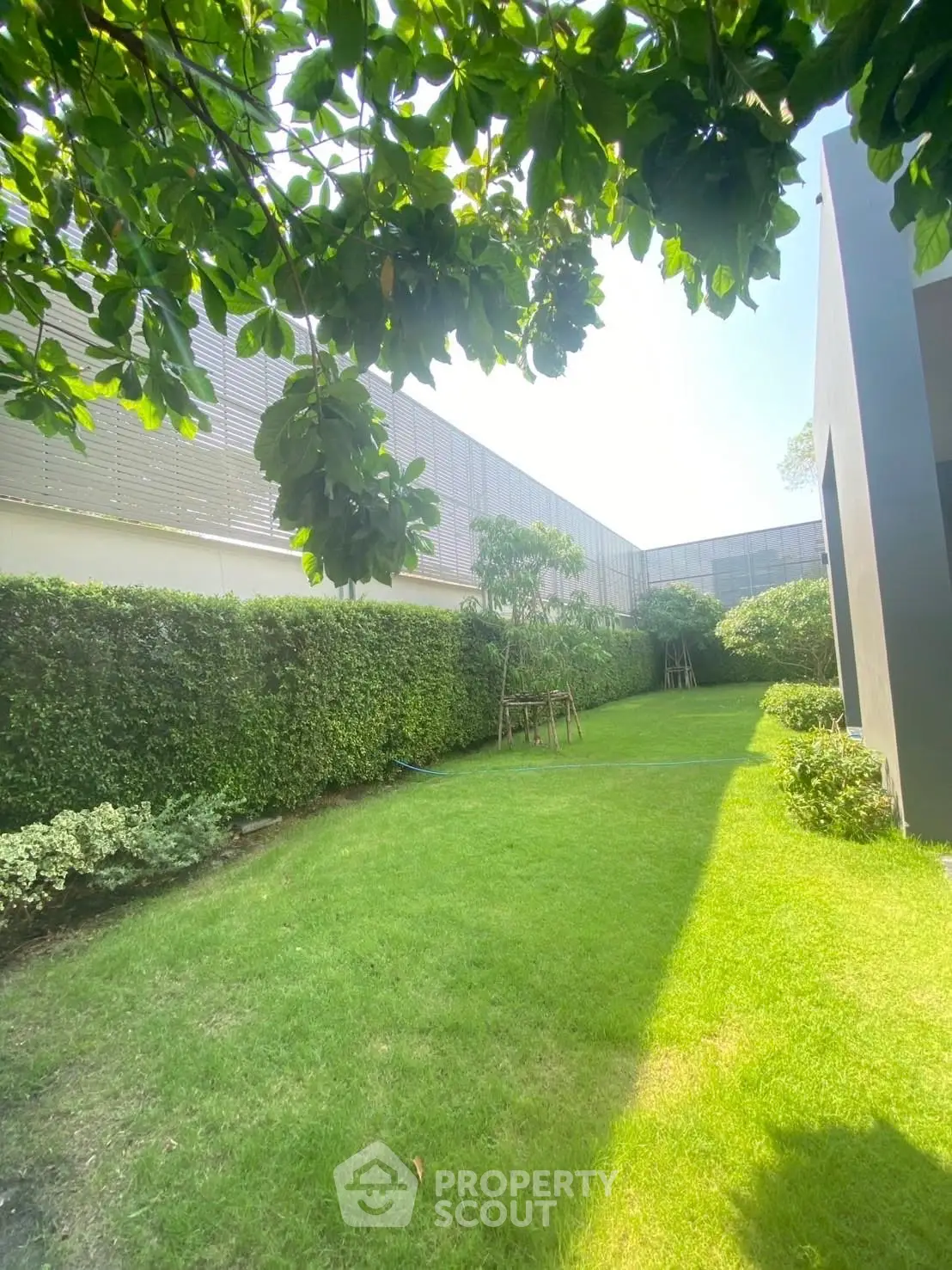 Lush green garden with manicured lawn and modern building exterior, perfect for relaxation and outdoor activities.