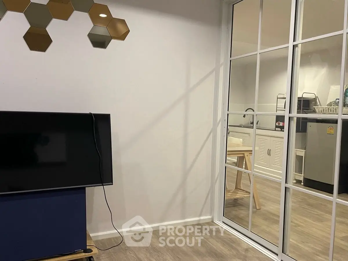 Modern living room with TV and view into stylish kitchen