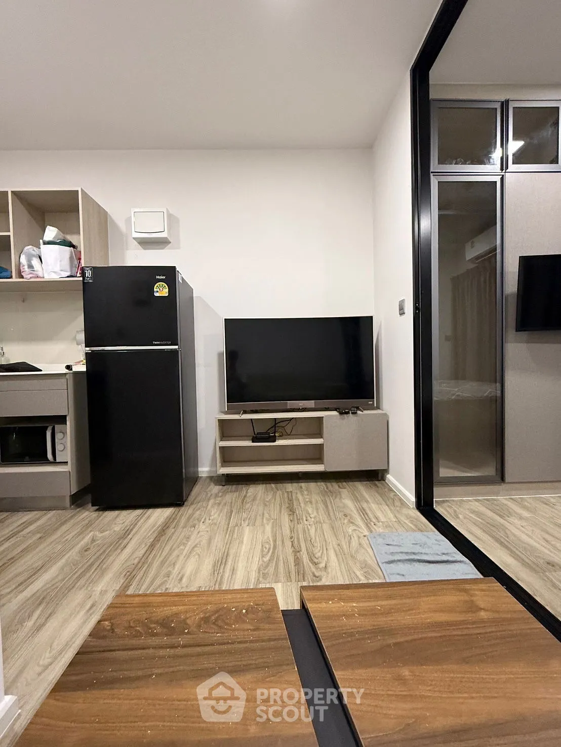 Modern studio apartment with sleek kitchen and cozy living area, featuring wood flooring and contemporary design.