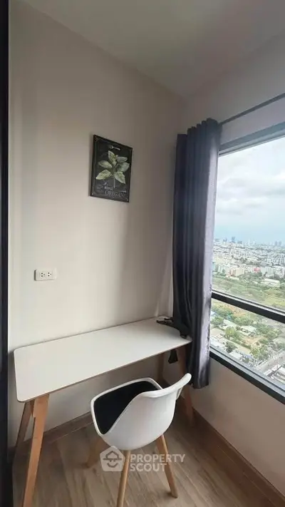 Modern study nook with a stunning city view, featuring a sleek desk and chair by a large window.