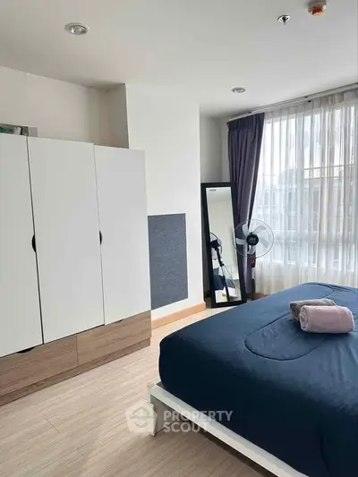 Modern bedroom with large window, stylish wardrobe, and cozy bed in a bright apartment.