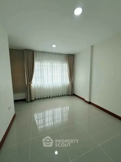 Spacious empty room with large window and elegant curtains, perfect for customization.