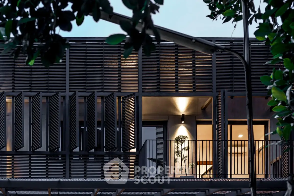 Modern architectural facade with sleek design and illuminated balcony, showcasing contemporary urban living.