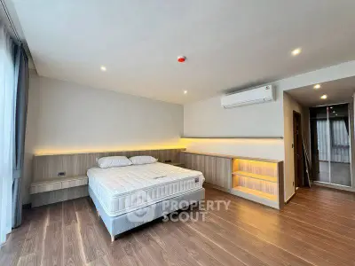 Spacious modern bedroom with wooden flooring and ambient lighting