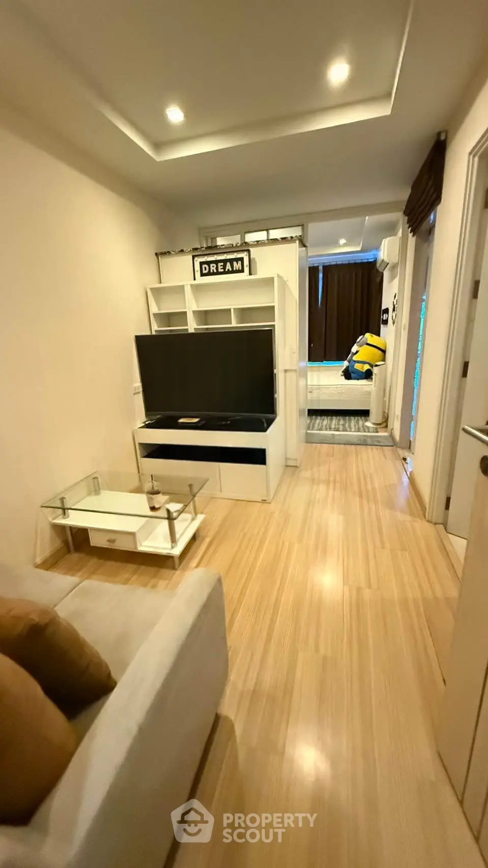 Modern living room with sleek wooden flooring and stylish TV unit in cozy apartment.