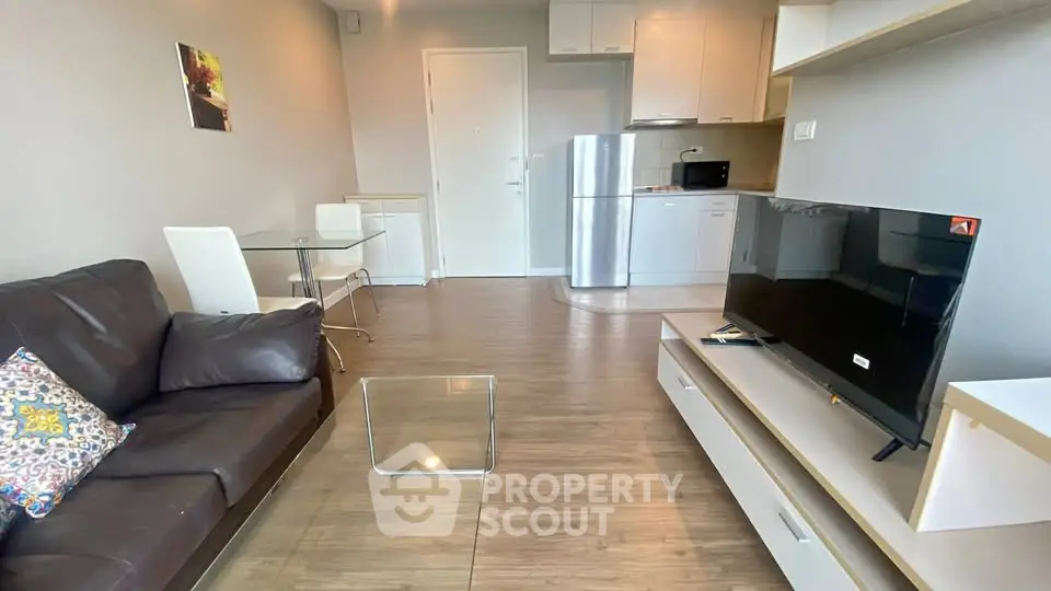 Modern living room with open kitchen, sleek furniture, and cozy decor.