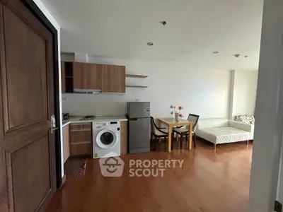 Modern open-plan living room with kitchen, featuring wooden flooring and contemporary furniture.