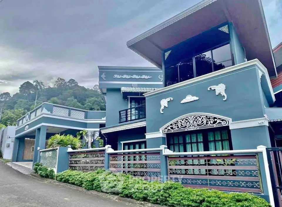 Stunning modern blue house with intricate white detailing and lush greenery, perfect for luxury living.