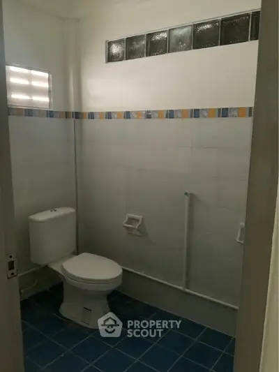 Spacious bathroom with modern toilet and tiled walls, ideal for comfortable living.