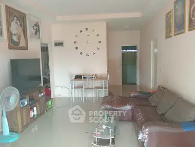 Spacious living room with modern decor and wall clock, featuring a cozy seating area and dining table.